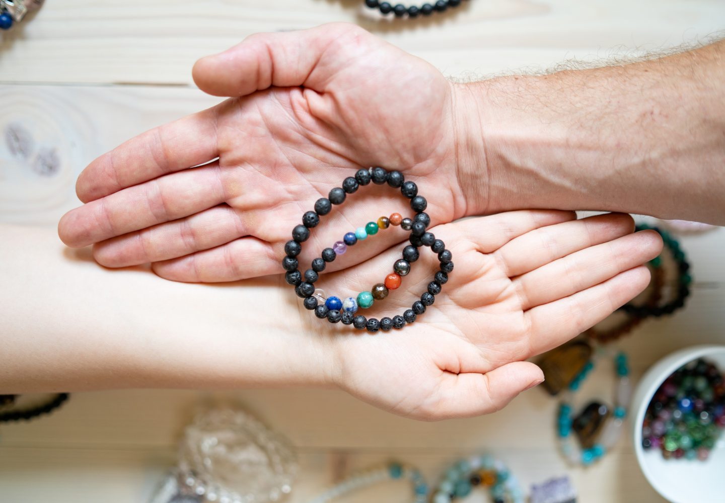 High angle view on male and female hands holding crystal gems bracelets handmade for love luck and charm healing energy