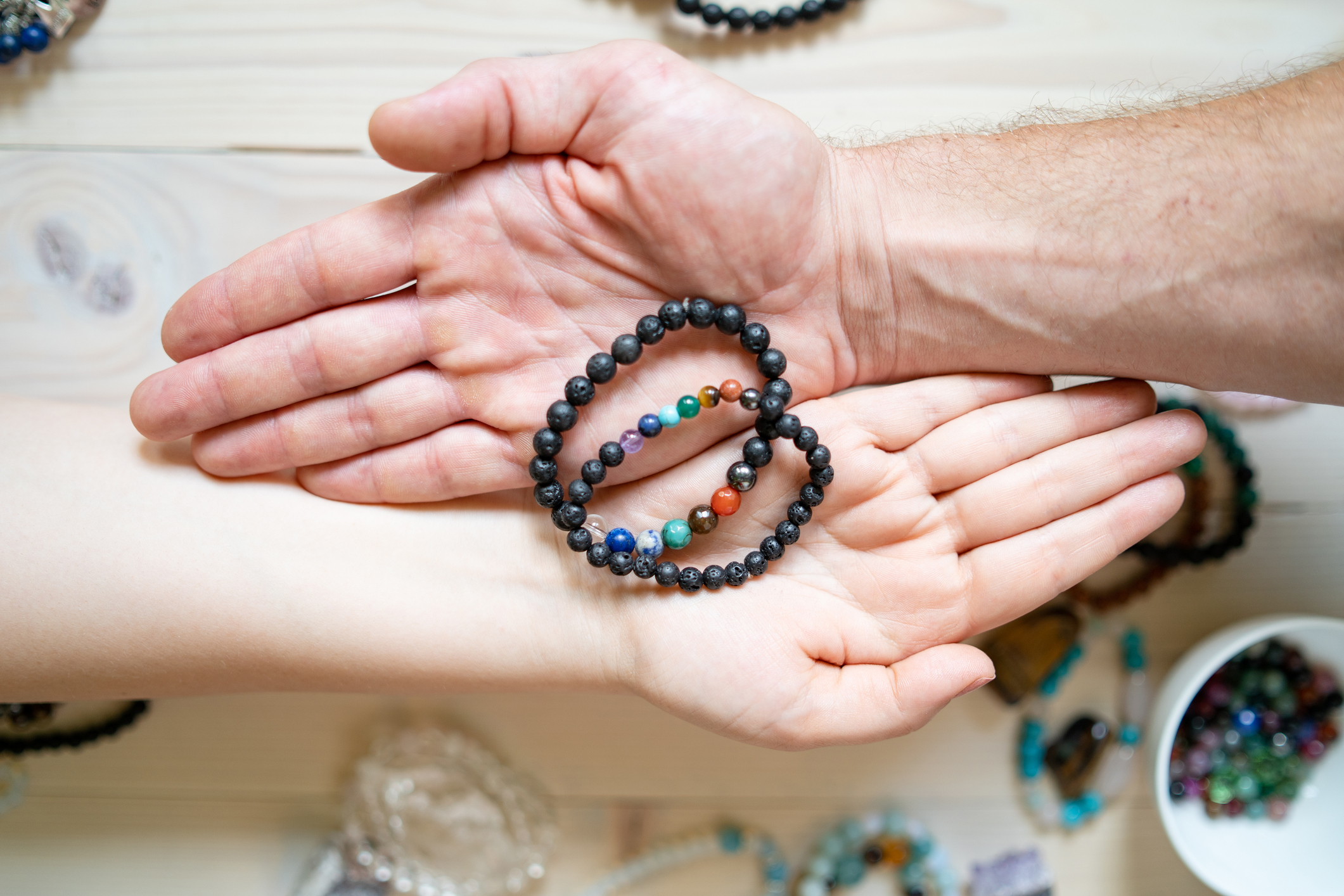 High angle view on male and female hands holding crystal gems bracelets handmade for love luck and charm healing energy